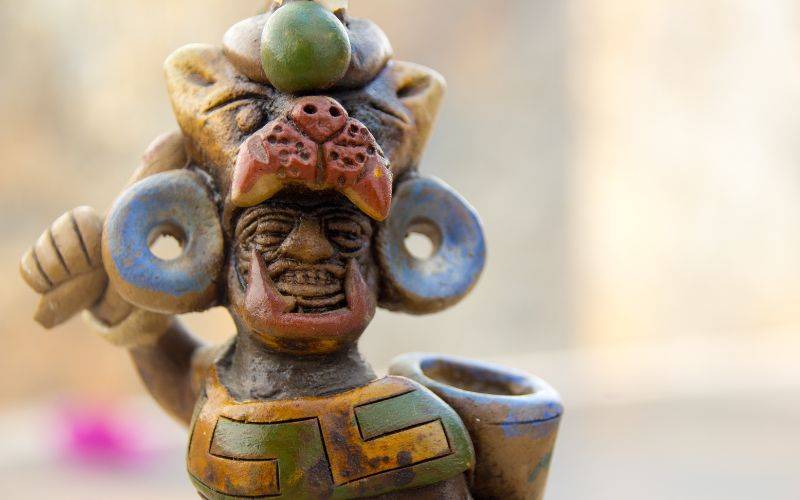 Patung figuratif yang menggambarkan anggota suku Aztec dengan hiasan bulatan seperti jeruk lemon di kepalanya