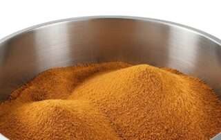 Tumpukan gula aren bubuk organik murni di dalam wadah stainless besar, bahan baku utama berkualitas untuk praktik menggunakan gula aren dalam kuliner dan aneka resep masakan modern.