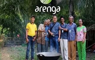 Sebuah foto kelompok delapan orang (tujuh pria dan satu wanita) dengan berbagai pakaian, berdiri bersama di tengah hutan pohon aren yang lebat di jalan setapak tanah. Mereka berkumpul mengelilingi kuali besar mengepul di atas tungku api kayu sederhana. Latar belakang menunjukkan pepohonan aren yang rimbun dan gubuk kayu. Di bagian tengah atas gambar terdapat logo melingkar daun aren hijau Arenga dengan teks 'arenga' berwarna putih. Seorang pria memegang botol nira biru dan pria lainnya memberikan acungan jempol.